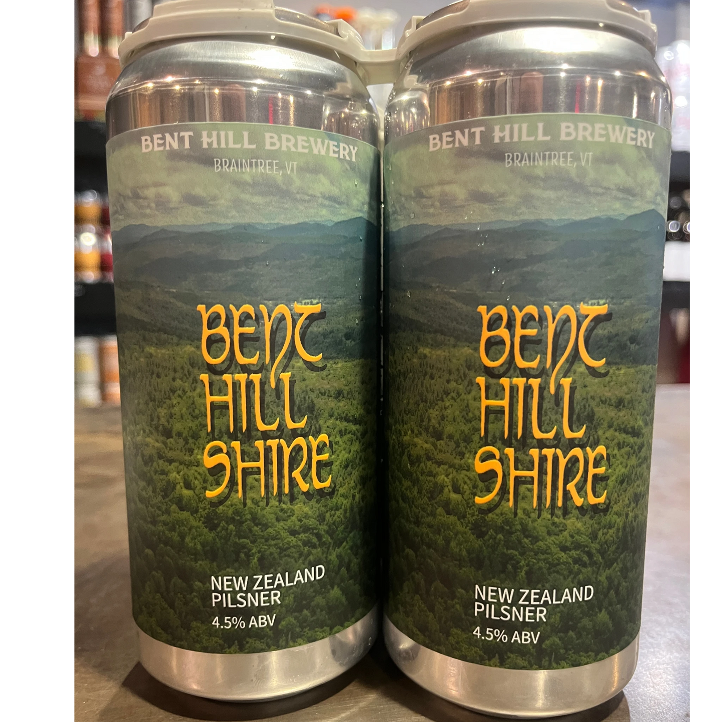 Stowe Public House & Bottle Shop: Bent Hill Shire New Zealand Pilsner beer cans, 4.5% ABV, featuring a landscape of green hills and yellow text.