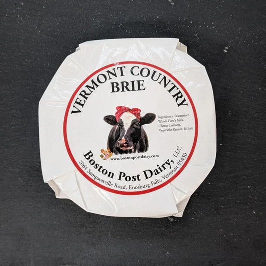 Stowe Public House & Bottle Shop Vermont Country Brie cheese with a cow illustration wearing a red bandana.